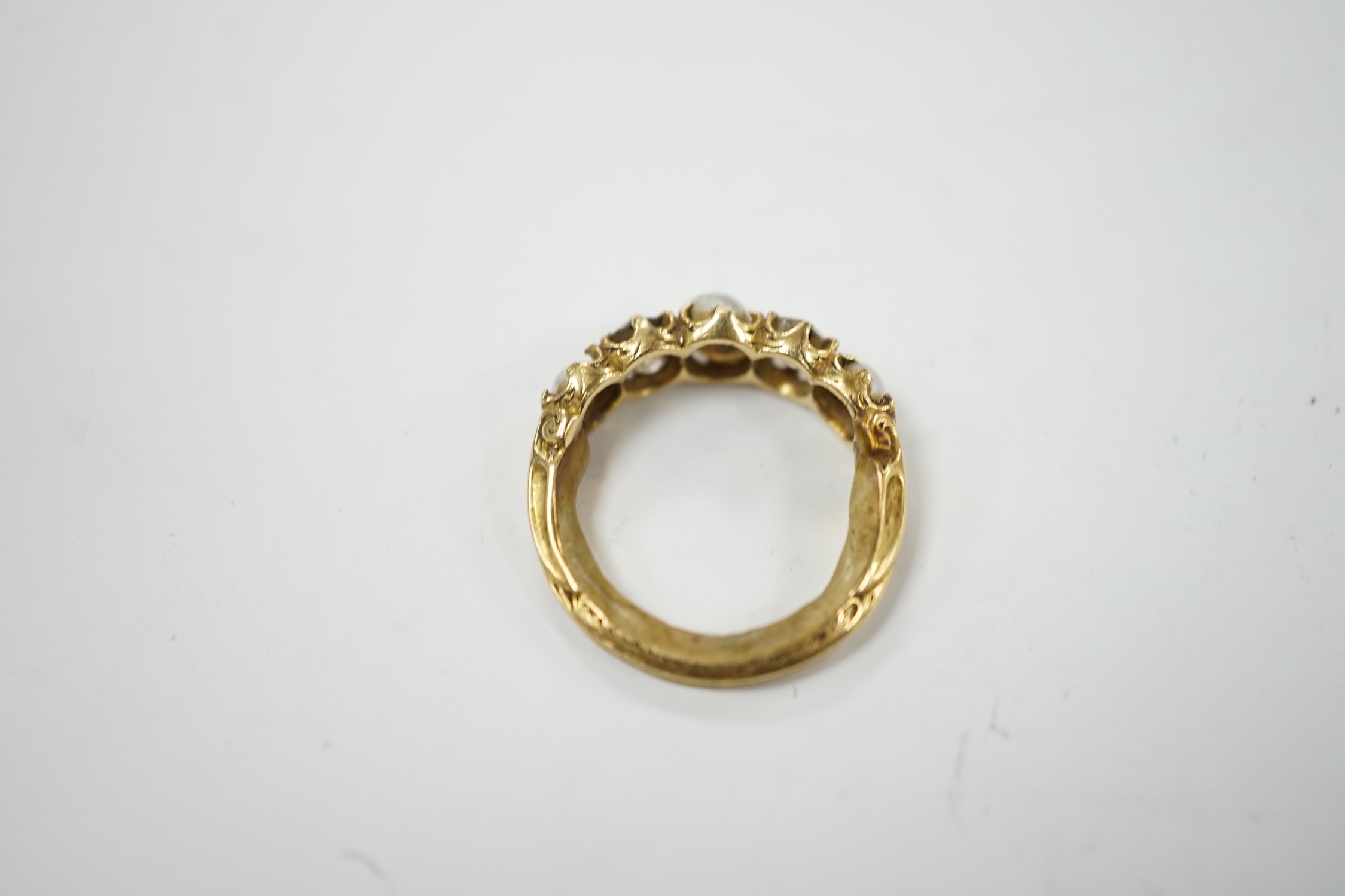 A late Victorian yellow metal and graduated three stone split pearl and two stone diamond set half hoop ring, with unusual wax? insert to the shank, size F, gross weight 3.2 grams.